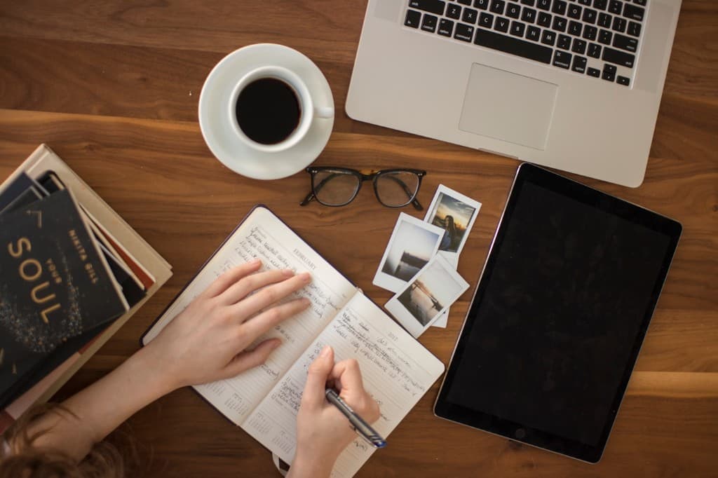 Flat lay of a creative desk with coffee, notebook, and laptop